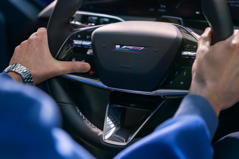 Close-up of a Man About to Press the V-Button on the 2026 OPTIQ-V Steering Wheel | Allen Cadillac in Monroe MI