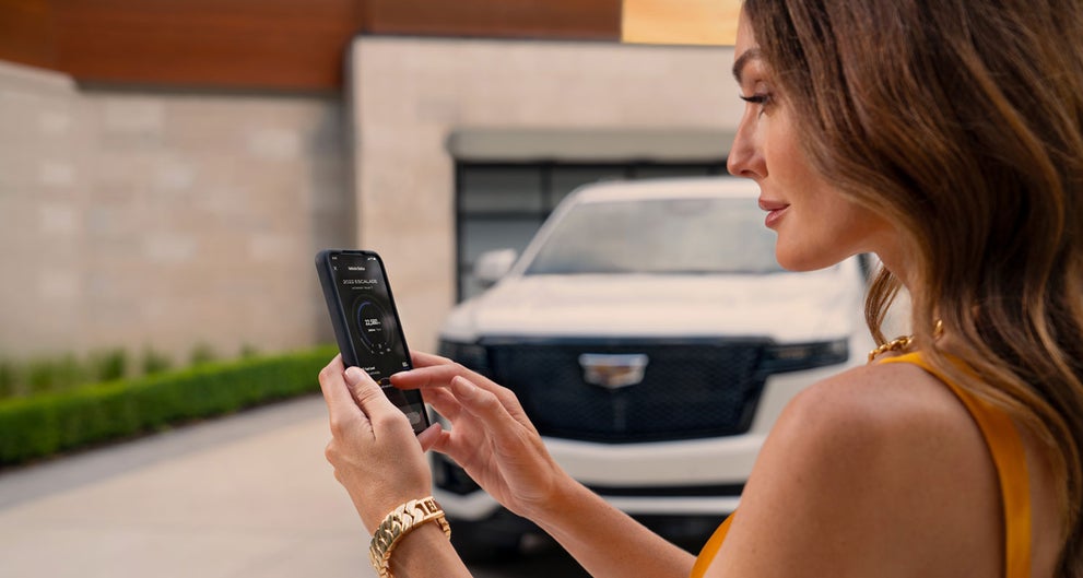 lady checking her mobile with a Cadillac vehicle background | Allen Cadillac in Monroe MI